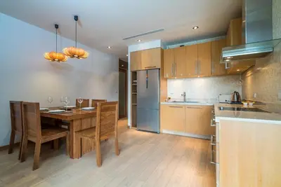 a kitchen with a wooden table and wooden chairs at Bright beachfront retreat in Bang Tao in Bang Tao Beach