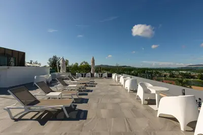 a row of lounge chairs on the roof of a building at Oceanstone by Holy Cow, studio, next building view in Bang Tao Beach