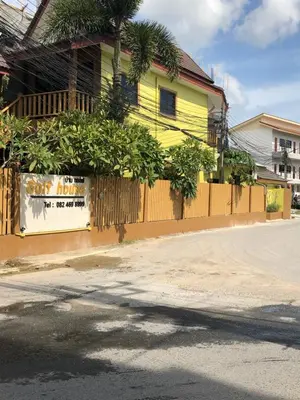 a yellow building with a sign on the side of a street at Golf House in Ban Bang Phai
