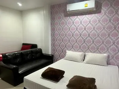 a bedroom with a bed and a black leather couch at Golf House in Ban Bang Phai