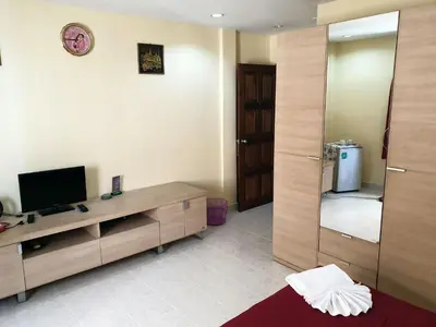 a living room with a television and a mirror at Oasis Guesthouse & Bar in Karon Beach