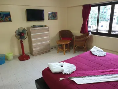 a bedroom with a purple bed and a room with a desk at Oasis Guesthouse & Bar in Karon Beach