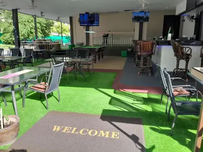 a restaurant with tables and chairs and a welcome sign at Oasis Hostel & Bar in Karon Beach