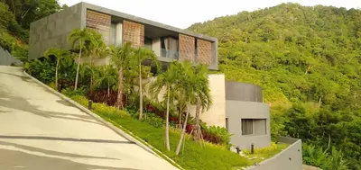 a building with palm trees in front of a mountain at The Cube Ocean View Pool Villa Kalim in Patong Beach