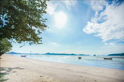 a beach with two boats in the water at Blue Beach Apartment in Rawai Beach