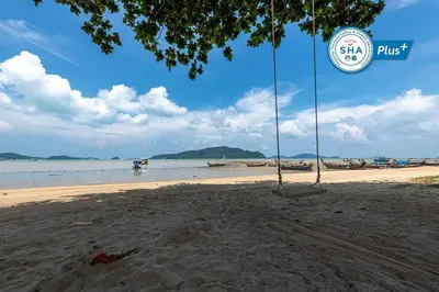 a swing on a beach with the ocean in the background at Blue Beach Apartment in Rawai Beach