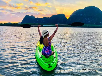 a woman in a kayak on the water with her arms up at Jamesbond Bungalow Koh Panyee in Ko Panyi