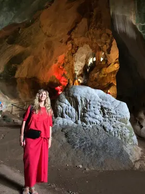 a woman in a red dress standing in front of a cave at Jamesbond Bungalow Koh Panyee in Ko Panyi