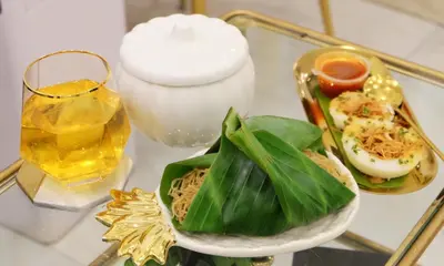 a glass table with a plate of food and a drink at Isara Boutique Hotel and Cafe in Phuket Town