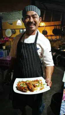 a man in an apron holding a plate of food at PP Red Tuna Hut in Phi Phi Don