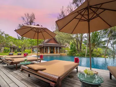 a pool with two beds and umbrellas on a deck at Villa Chada in Kamala Beach