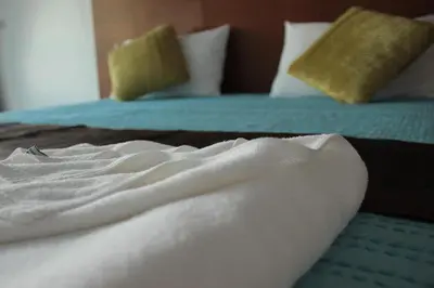 a bed with white sheets and pillows on it at Sukcheewa Residence Phuket in Patong Beach