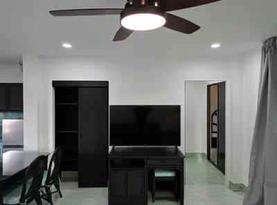 a living room with a flat screen tv and a ceiling fan at Patong Sunbeach Mansion in Patong Beach