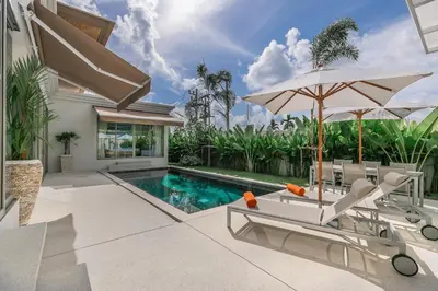 a house with a swimming pool and a patio with an umbrella at Modern 3BR Villa with Private Pool and BBQ in Bang Tao Beach