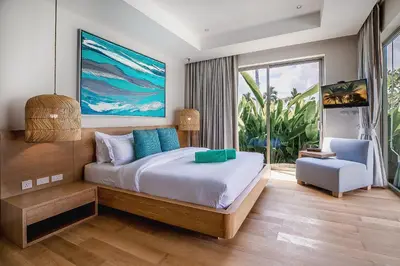 a bedroom with a large bed and a chair at Modern 3BR Villa with Private Pool and BBQ in Bang Tao Beach
