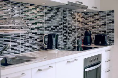 a kitchen with white cabinets and a tile wall at Modern 3BR Villa with Private Pool and BBQ in Bang Tao Beach