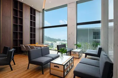 a lobby with chairs and a table and a large window at Mida Grande Resort Phuket Official Account in Surin Beach