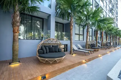 a room with a couch and palm trees in a building at Citygate Kamala Resort and Residence - Official Account in Kamala Beach