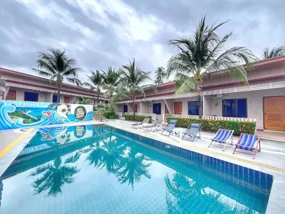 a pool at a hotel with chairs and palm trees at The Passion Nest - SHA Plus Certified in Phuket Town