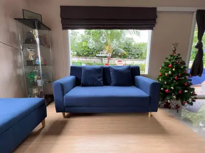 a living room with a blue couch and a christmas tree at The Passion Nest - SHA Plus Certified in Phuket Town