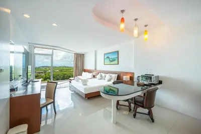 a hotel room with a bed and a table and chairs at The View Rawada Phuket in Rawai Beach