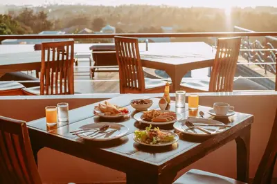 a table with plates of food on a balcony at The View Rawada Phuket in Rawai Beach