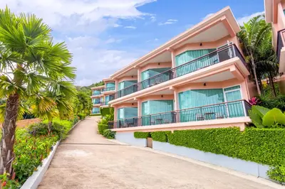 a building with balconies and palm trees next to a sidewalk at The View Rawada Phuket in Rawai Beach