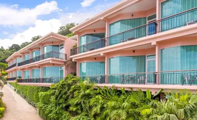 a pink building with balconies and trees at The View Rawada Phuket in Rawai Beach