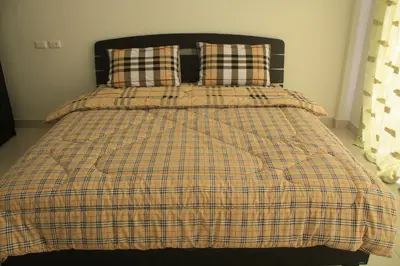a bed with a plaid blanket and two pillows at We Love Kata in Kata Beach