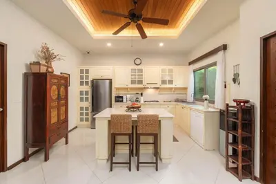 a kitchen with white cabinets and a ceiling fan at VILLA LETI 22 meters Pool Naiharn Beach in Rawai Beach