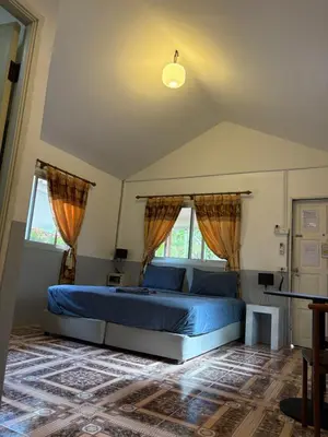 a bedroom with a blue bed and two windows at Ban Elephant Blanc Bungalow in Kata Beach