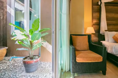 a plant in a pot next to a chair in a room at Baan PhuAnda Phuket in Phuket Town