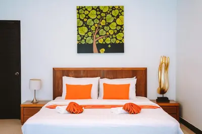 a bedroom with a bed with orange pillows and a painting at Layantara Villas in Layan Beach