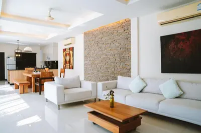 a living room with white furniture and a brick wall at Layantara Villas in Layan Beach
