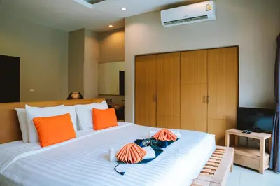 a bedroom with a large white bed with orange pillows at Layantara Villas in Layan Beach