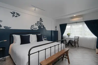 a bedroom with a bed with a bench and a table at Blu Monkey Boutique Phuket Town in Phuket Town