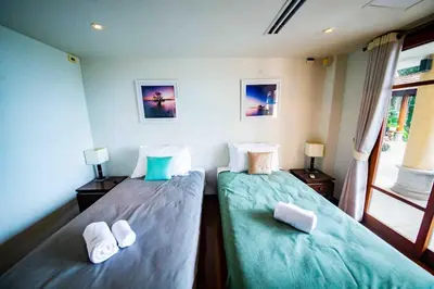 two twin beds in a room with a window at Luxury 4 bedrooms Villa with Seaview Infinity Pool overlooking Surin Beach in Surin Beach