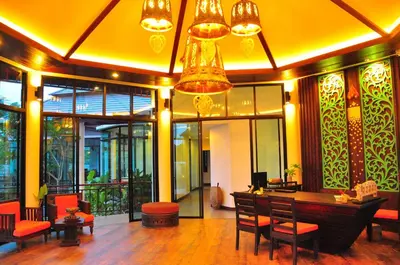 a lobby with a table and chairs and a chandelier at Navatara Phuket Resort in Rawai Beach