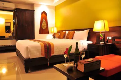 a bedroom with two beds and a table with wine glasses at Navatara Phuket Resort in Rawai Beach