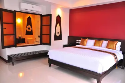 a bedroom with a large bed and a red wall at Navatara Phuket Resort in Rawai Beach