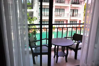 a balcony with a table and chairs and a building at Navatara Phuket Resort in Rawai Beach