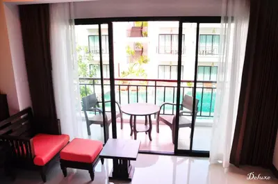a room with a balcony with a table and chairs at Navatara Phuket Resort in Rawai Beach