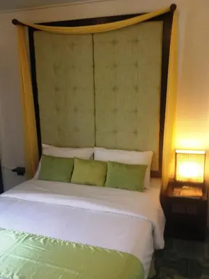 a bed with a headboard with two green pillows at Bliss Resort Krabi in Klong Muang Beach