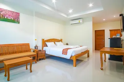 a bedroom with a bed and a bench and a desk at Prayai Changthai Resort in Phuket Town