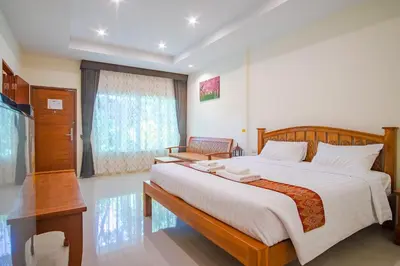 a bedroom with a large bed and a desk at Prayai Changthai Resort in Phuket Town