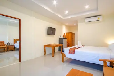 a bedroom with a bed and a table and a mirror at Prayai Changthai Resort in Phuket Town