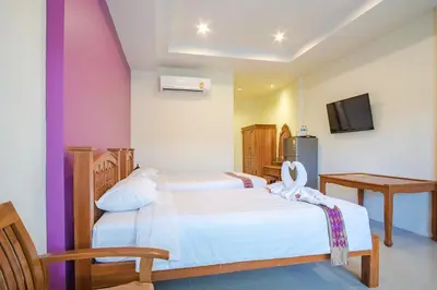 a bedroom with two beds and a tv at Prayai Changthai Resort in Phuket Town