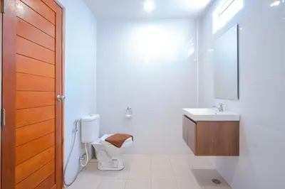 a white bathroom with a toilet and a sink at Prayai Changthai Resort in Phuket Town
