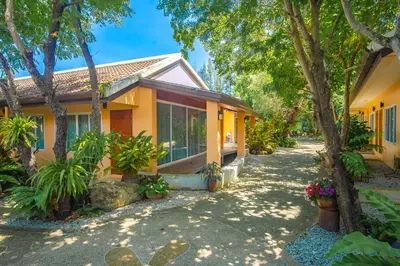 a yellow house with trees and plants at Prayai Changthai Resort in Phuket Town