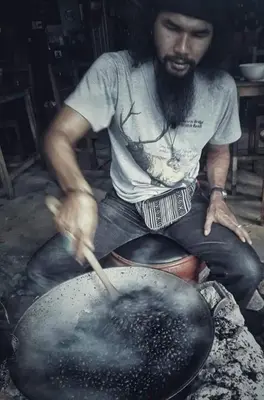 a man is cooking in a pan with a spatula at Ko Yao Noi Sabai Bungalows in Ko Yao Noi